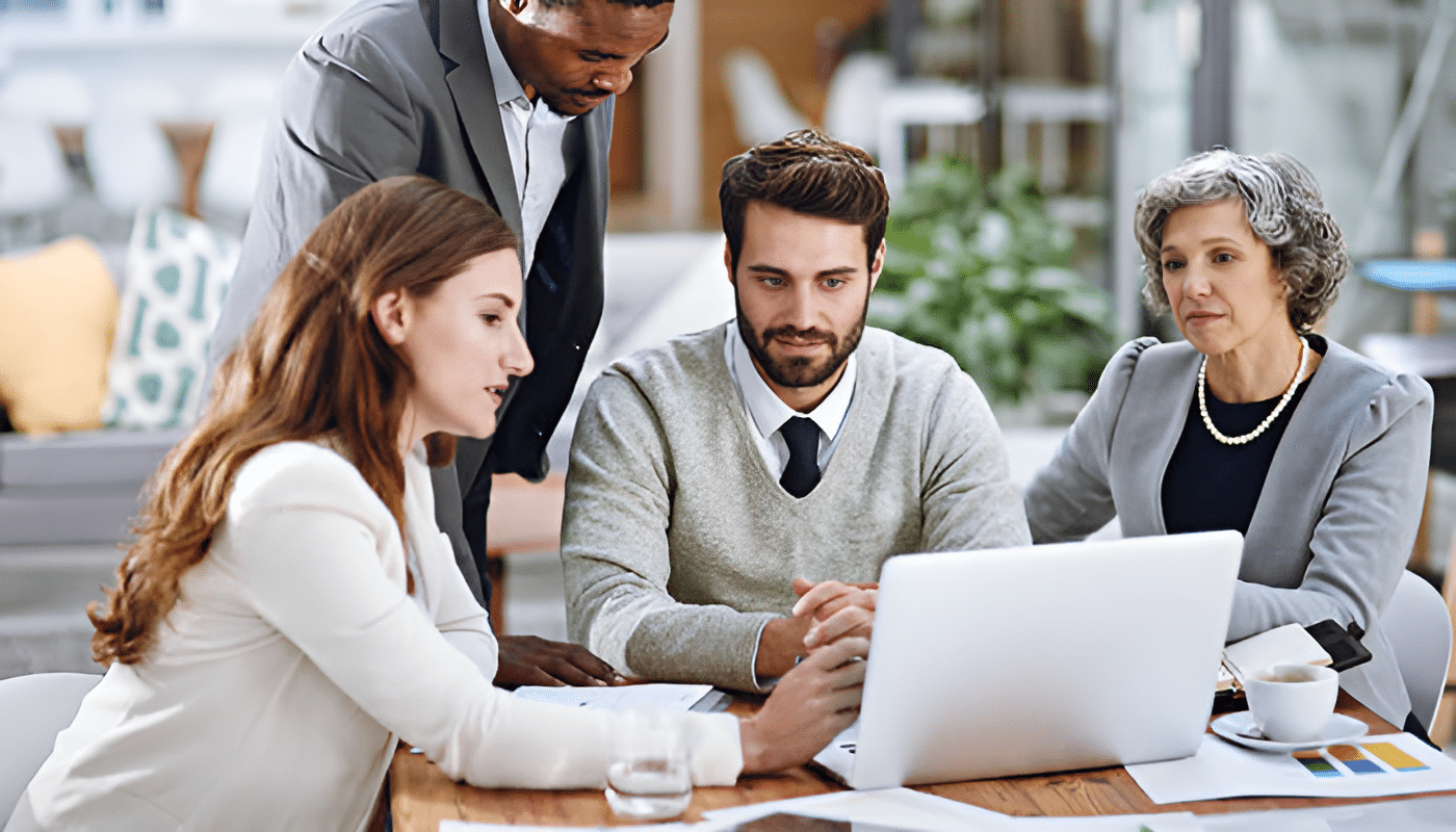 A team of professionals collaborating on creative content strategy using a laptop in a modern office setting.