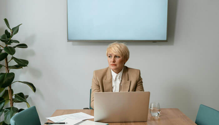 A businesswoman reflecting during a meeting, exemplifying how leadership skills involve emotional regulation and decision-making in high-pressure environments.