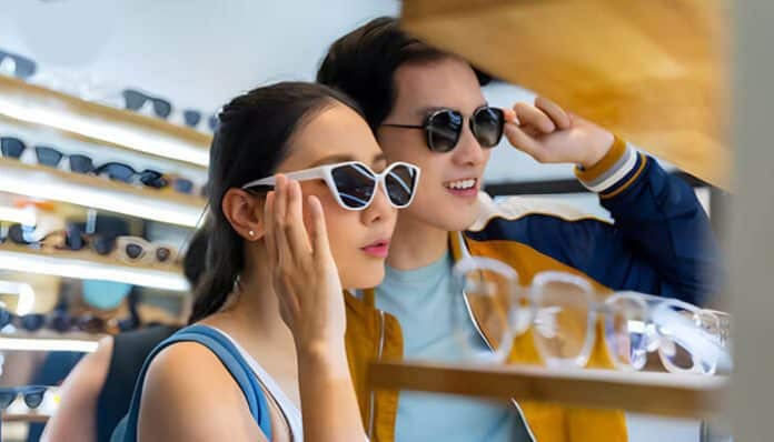 Young couple trying on stylish sunglasses in a store, exploring options to choose the right eyewear for comfort, vision, and fashion.