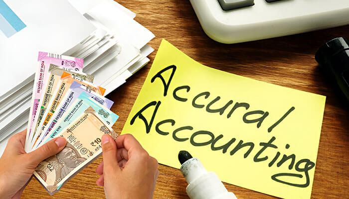 Cash vs accrual accounting concept with Indian currency notes, documents, and a sticky note labeled accrual accounting