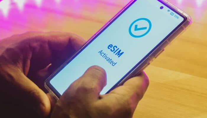 A person holding a smartphone showing eSIM activated on the screen, indicating digital SIM activation.
