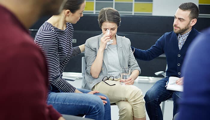Emotional group support scene showing people comforting a woman, an example of visual storytelling that builds empathy and trust
