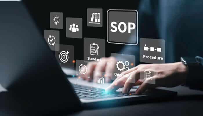 Person typing on a laptop with digital SOP icons, illustrating how standard operating procedures help optimize team efficiency through clear workflows and automation.