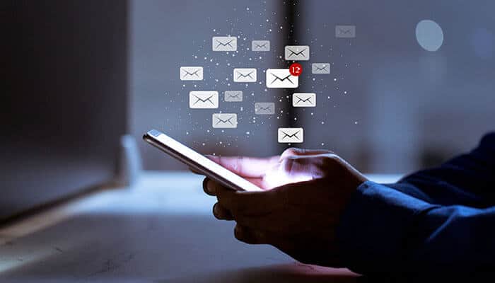 Person holding a smartphone with floating email icons, representing custom email design and digital communication in a modern inbox environment.