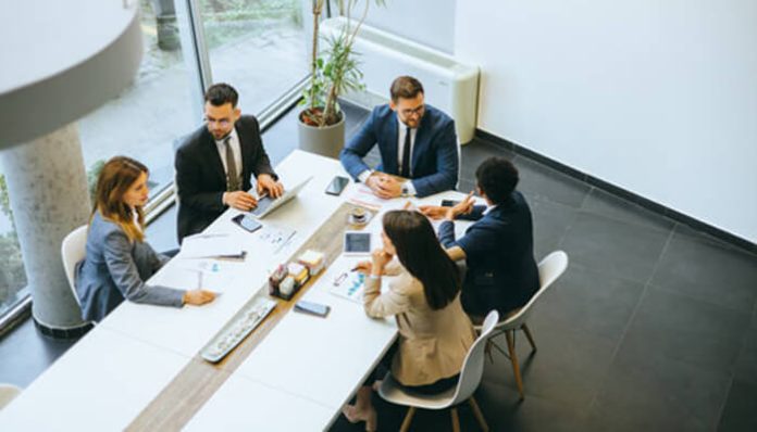 A group of business executives in a formal boardroom meeting, discussing strategies to prevent and resolve Shareholder Disputes.