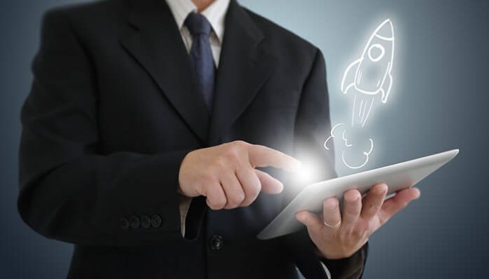 Business professional using a digital tablet with a glowing rocket icon, symbolizing innovation and growth to boost your startup success.