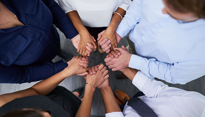 Team holding hands in unity symbolizing trust and collaboration at a customer-centric insurance startup focused on building strong client relationships.