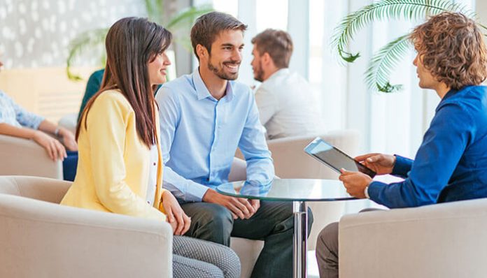 A customer couple meeting with an advisor at a customer-centric insurance startup, discussing personalized insurance solutions with digital tools.