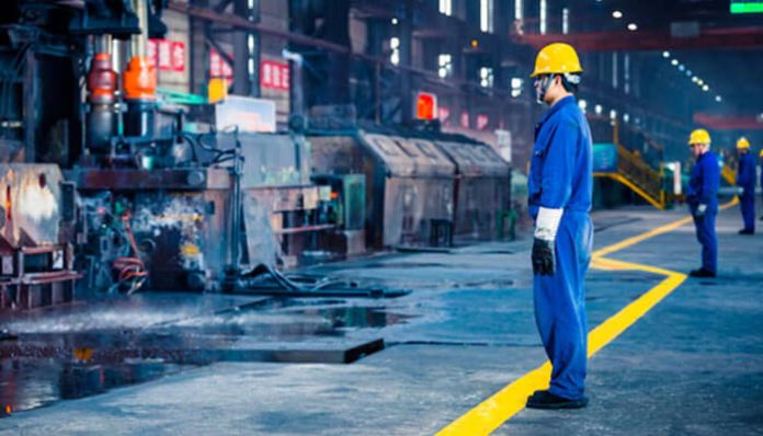 Workers in protective gear inside a factory setting, representing buying industrial supplies online for manufacturing and safety needs.