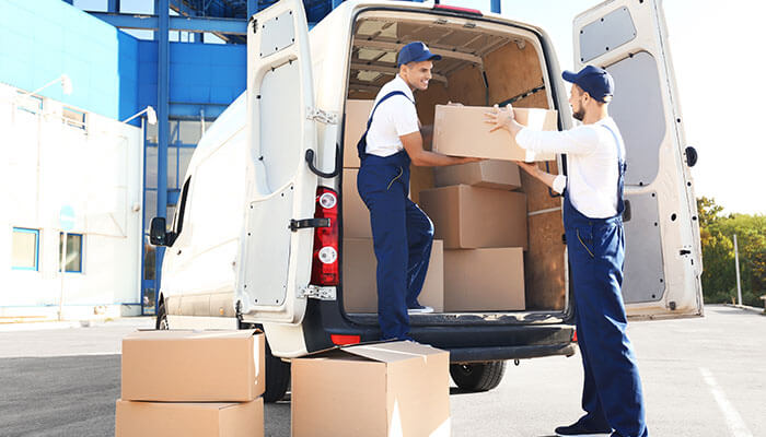 Workers unloading delivery boxes from a van, showing the convenience of buying industrial supplies online for fast shipping and logistics