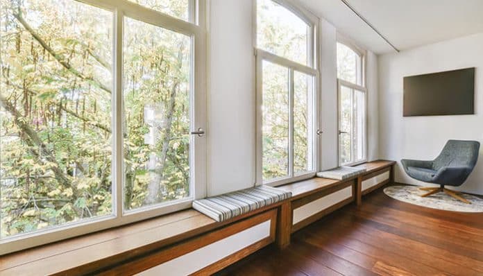 Modern living room with large glass panels featuring uPVC windows low-maintenance design, allowing natural light and a clear outdoor view.