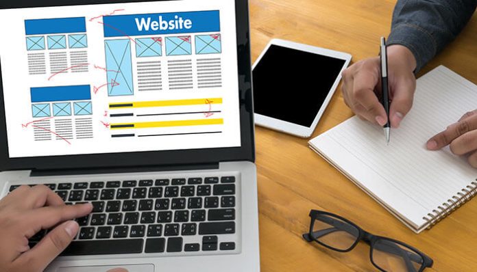 Designer planning layout on laptop and notebook to create a business website with limited budget and resources.