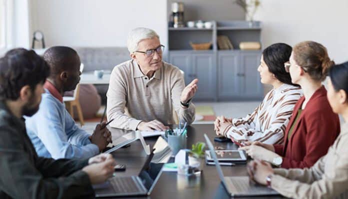 A diverse group of professionals having a meeting, with a focus on enhancing team performance without burnout, fostering communication and collaboration.