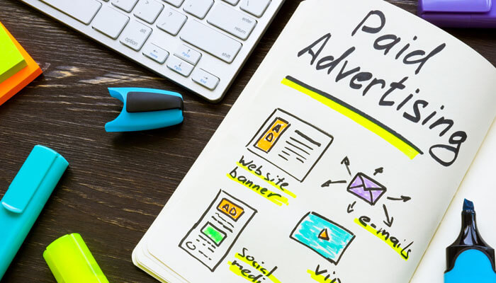 Invest in Targeted Paid Advertising - Startupeditor | Startup Editor Notebook with paid advertising plan including website banners, emails, and social media, representing key digital strategies for startups.