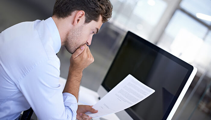 A businessman carefully reviewing a contract at his desk, highlighting the importance of reading fine print when Investing In Business Insurance.
