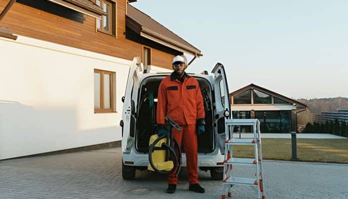 Technician standing beside service van with tools, representing how to digitize scheduling for mobile field teams using modern FSM solutions.