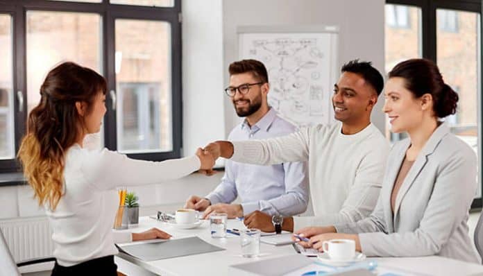 Business professionals engaging in a handshake during a meeting while selecting a recruitment agency for hiring decisions.