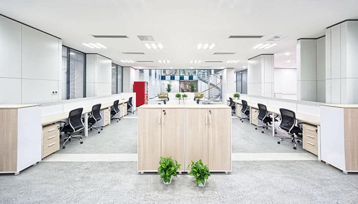 Bright energy-efficient office space with modern desks, ergonomic chairs, natural lighting, and indoor plants creating a sustainable work environment.