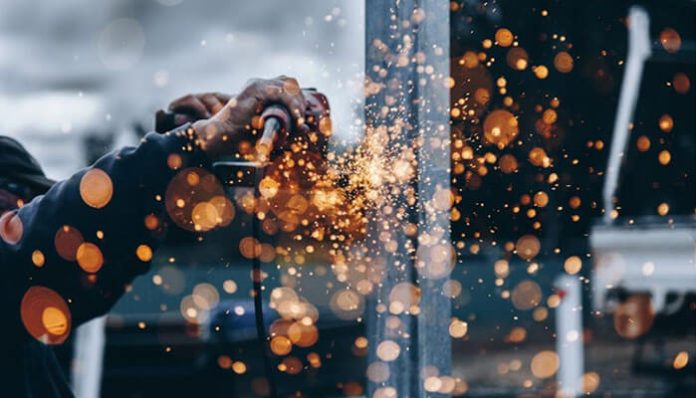 Industrial worker welding metal components with sparks flying, highlighting the durability and efficiency of quality used plate exchangers in industrial operations.