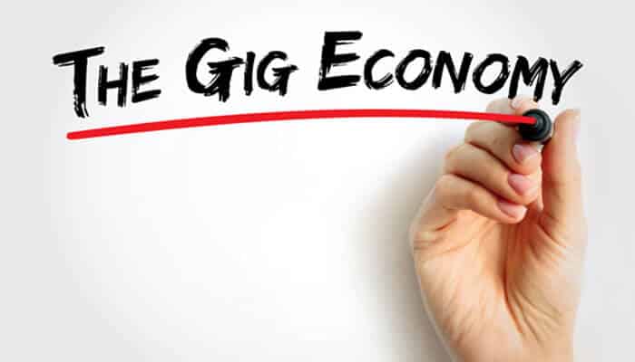 A hand underlining the Gig Economy with a marker, symbolizing the growing trend of gig work and the importance of loans for gig workers in the modern workforce.