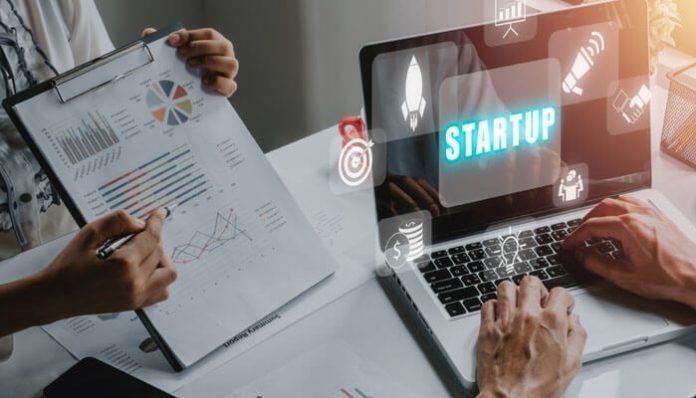 Startup scaling priorities shown with entrepreneurs analyzing charts and using a laptop with a startup growth concept on the screen