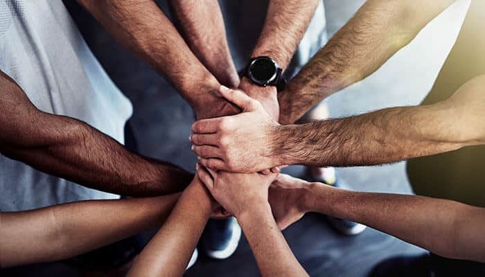 A group of people joining hands in unity, symbolizing teamwork, compassion, and the ripple effect of an act of kindness.