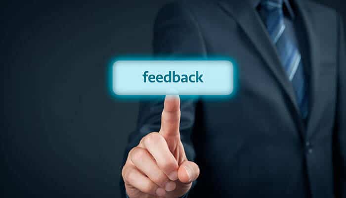 A professional clicking on a feedback button, symbolizing the importance of team performance without burnout by encouraging open and constructive feedback.