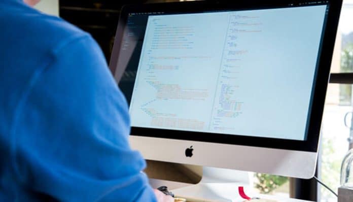 A developer working on a desktop computer displaying app code, representing the Enterprise AppGen platform’s role in simplifying rapid app creation for startups.
