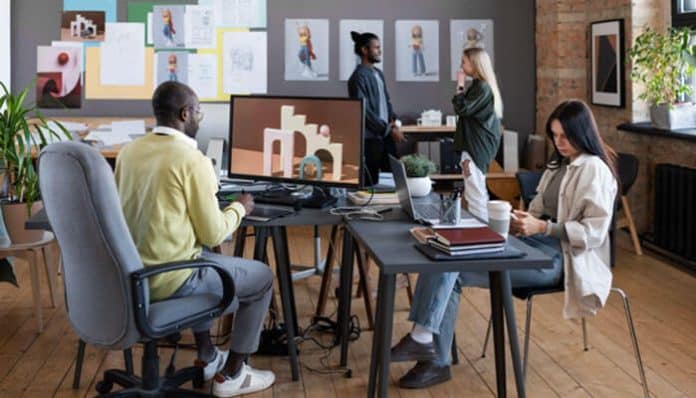 A modern startup office with employees collaborating and working at desks in ergonomic chairs, showcasing ergonomic workspaces for startups designed for comfort and productivity.