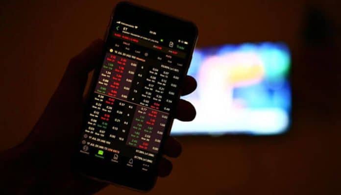 A person holding a smartphone displaying stock market charts and prices, representing real-time analysis and decision-making in swing trading.
