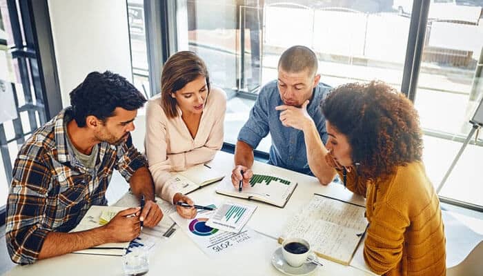 A diverse business team discussing charts and reports during a meeting, using asset tracking data to plan strategies and improve business efficiency.