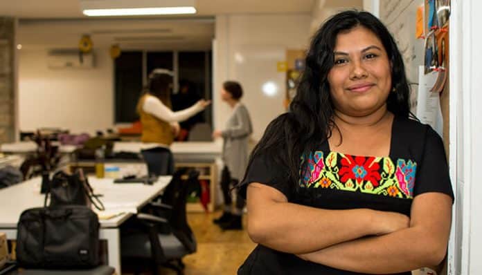 Confident Indigenous woman standing in a modern workspace, symbolizing leadership, inclusion, and Indigenous Awareness in professional environments.