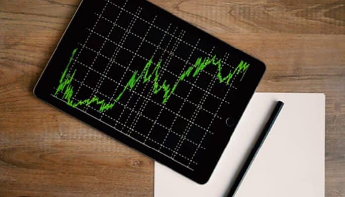 A tablet displaying an upward-trending financial graph on a wooden desk, symbolizing growth, performance tracking, and data-driven decisions for Business Survival.