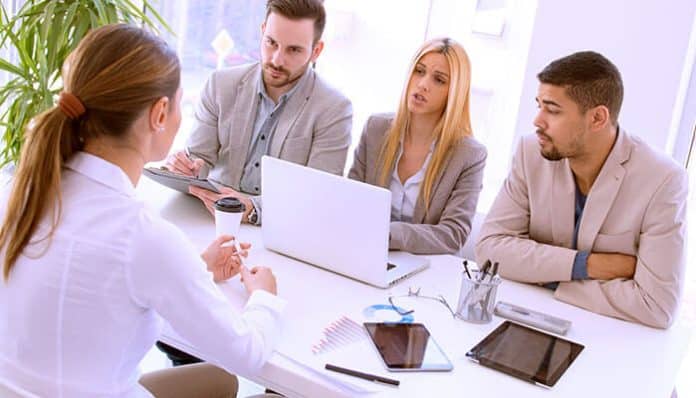 Hiring panel conducting a job interview with a candidate in a modern office setting demonstrating a structured hiring process to evaluate candidate quality.