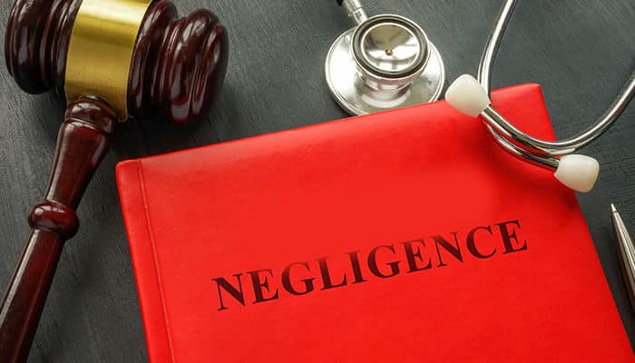 A red legal book titled Negligence is placed beside a judgeโs gavel and a stethoscope, symbolizing the legal and medical connection required to prove liability in a personal injury case