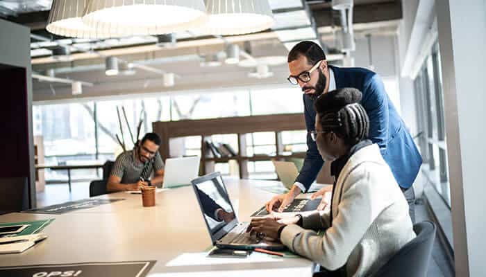 Manager guiding an employee during a meeting in a modern office environment illustrating collaboration and evaluation within a structured hiring process.