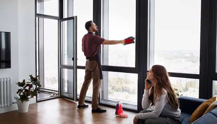Homeowner maintaining sleek aluminium windows in a bright apartment โ showcasing easy-care and energy-efficient Aluminium Windows in Scotland.