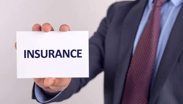 A business professional holding a card labeled “Insurance,” representing financial protection and professional insurance for dog trainers.