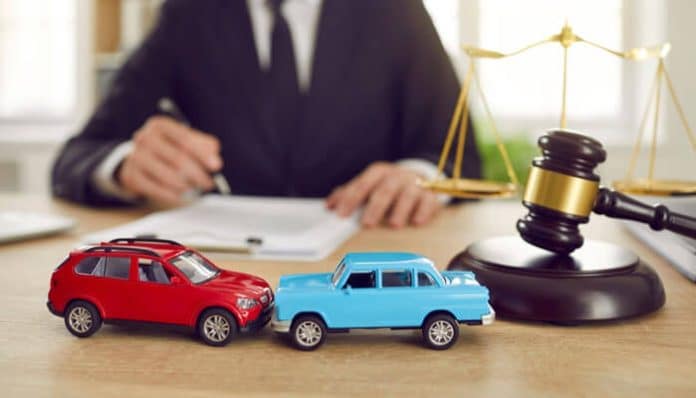 Two toy cars colliding in front of a gavel and legal documents on a desk, symbolizing how a car accident lawyer handles collision cases and legal claims for clients.