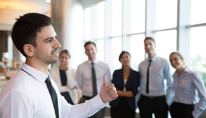A confident business professional giving a thumbs-up while addressing a team during a meeting, symbolizing leadership, teamwork, and strategies for Business Survival.