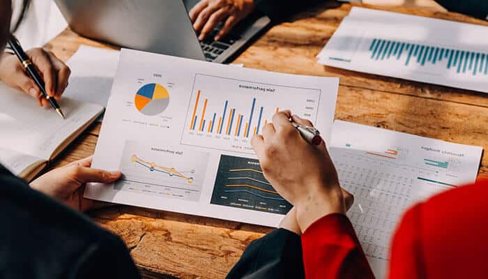 Team analyzing financial charts and performance reports at a meeting table showing collaborative finance skills under pressure.