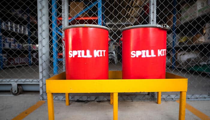 Two red containers labeled “Spill Kit” in an industrial setting, illustrating the use of portable spill kits for emergency safety.