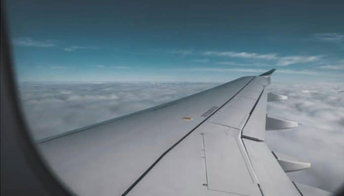 A view of an airplane wing flying above the clouds, symbolizing the comfort and luxury of traveling in business class to Europe