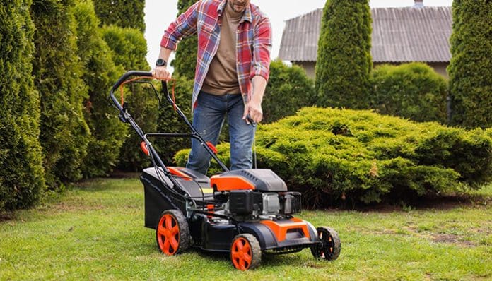 A homeowner using an electric lawn mower in the garden for eco-friendly lawn care.