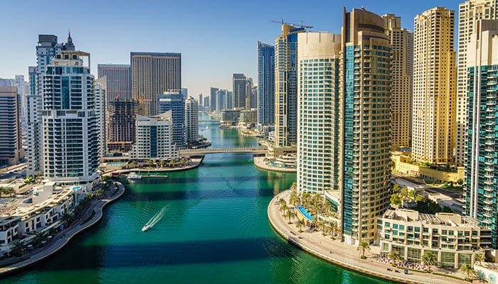 Dubai Marina with modern skyscrapers and a boat on the water, showcasing the vibrant Dubai skyline and business environment for Dubai free zone business setup