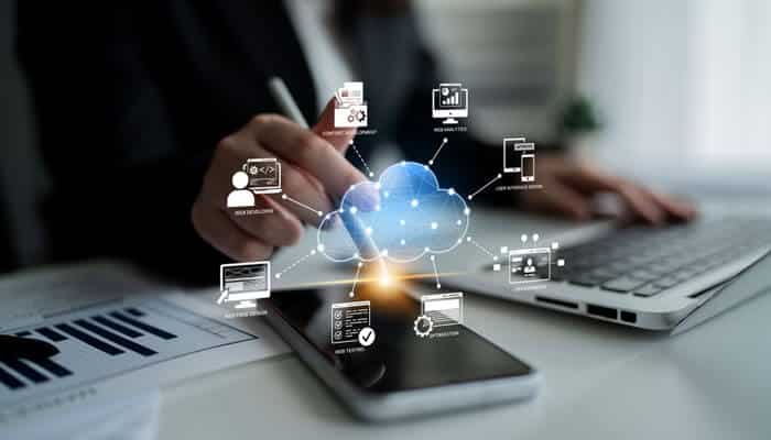 Future trends in association management shown through cloud technology icons while a professional works on a laptop and smartphone.