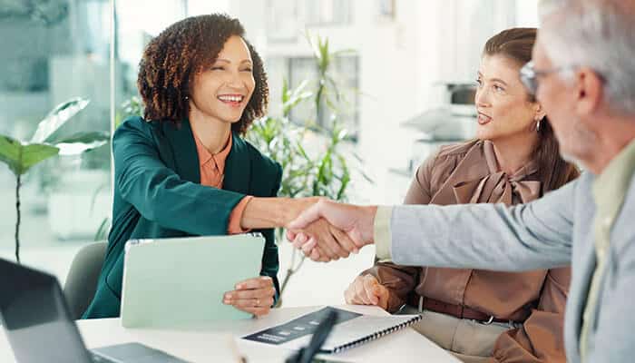 Business professionals shaking hands during a meeting symbolizing collaboration trust and partnership for scaling operations in a real estate startup.
