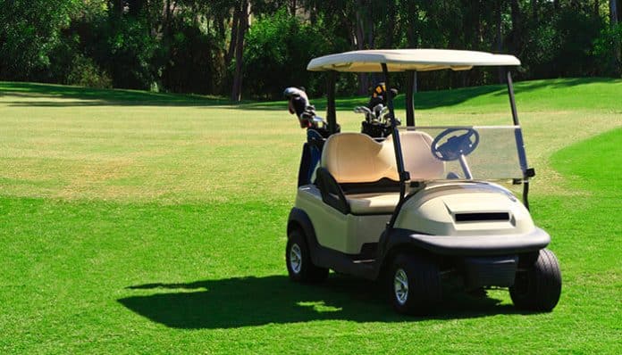 A golf cart parked on a green fairway, illustrating traditional uses for golf carts before their modern applications in communities and workplaces.