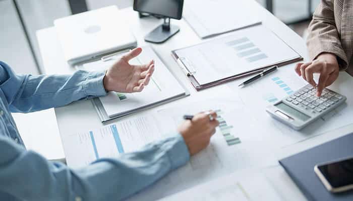 Business professionals reviewing data with a calculator and digital reports, demonstrating how smart technology in hospitality supports better decision-making and efficiency