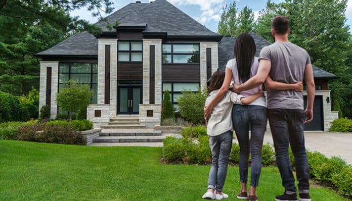 A family standing together and looking at a beautiful house, symbolizing home upgrade planning for families aiming to create their dream living space.